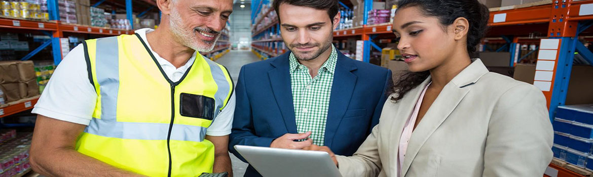 Warehouse worker and two business colleagues reviewing information on a tablet