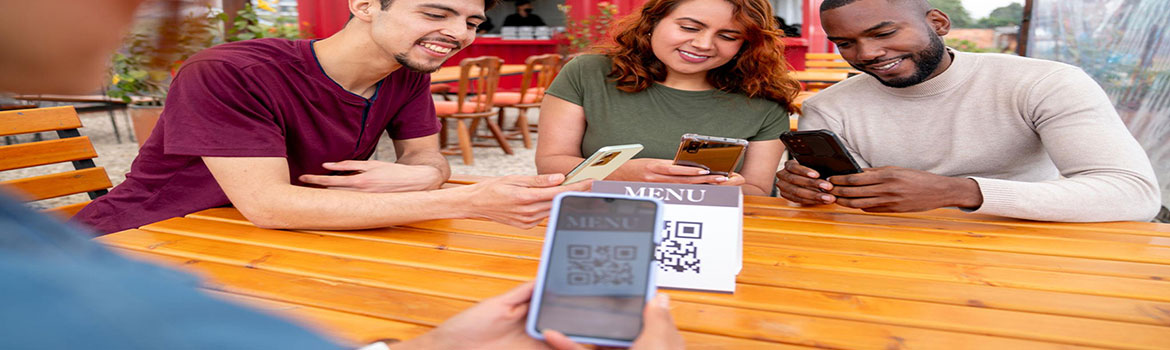Friends at an outdoor café table scanning a QR code menu with their phones